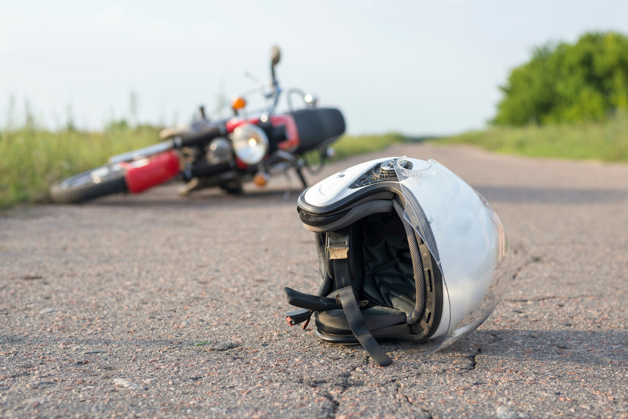 Photo of helmet and motorcycle on the road, the concept of road accidents