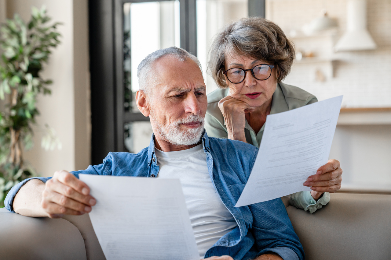 Senior old elderly spouses grandparents reading documents, having issue problem debt with money loss, doing paperwork together at home. Mortgage, loan and commerce procedures